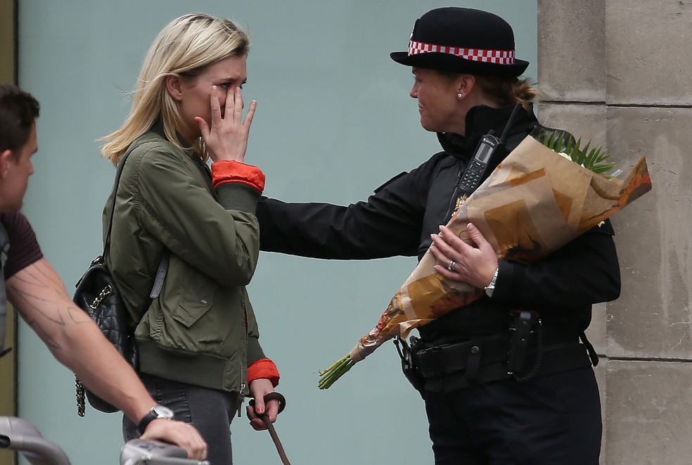  Mulher chora ao pedi para policial levar flores ao local do atentado na London Bridge (Foto:  Daniel LEAL-OLIVAS / AFP)