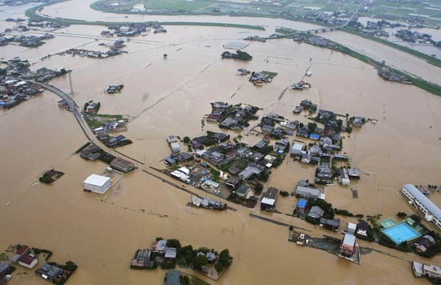 Casas parcialmente submersas após enchente do Rio Yabe, no topo, em Yanagawa, na província de Fukuoka, no Japão, neste sábado (14) (Foto: Kyodo News/AP)