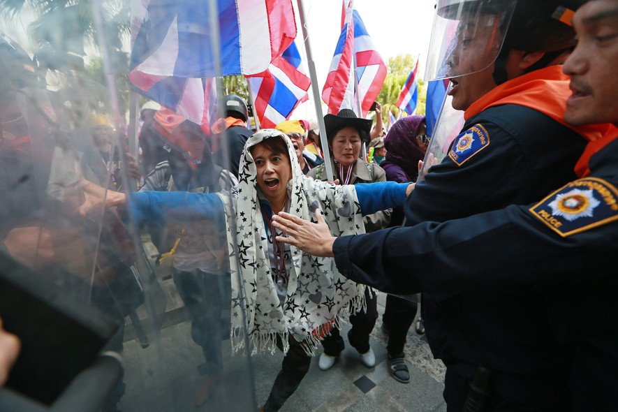 Agentes de segurança da Tailândia tentam conter manifestantes durante protesto  contra o governo em frente ao Departamento de Investigação Especial em Bangcoc. Na semana passada,  o órgão decidiu congelar as contas bancárias dos líderes dos protestos