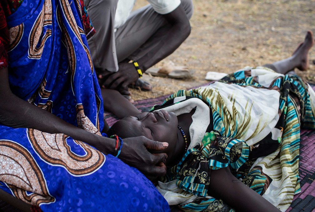 Parentes consolam mulher doente que aguarda atendimento em clínica improvisada em em Thaker, no Sudão do Sul, em março de 2017  (Foto: Siegfried Modola/ Divulgação Médicos Sem Fronteiras)