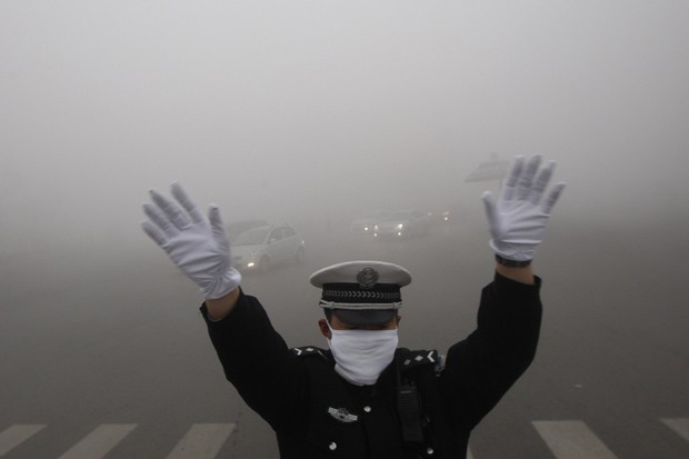   Policial faz sinal para motoristas na cidade de Harbin, na China, em meio à poluição. (Foto: Reuters/China Daily)
