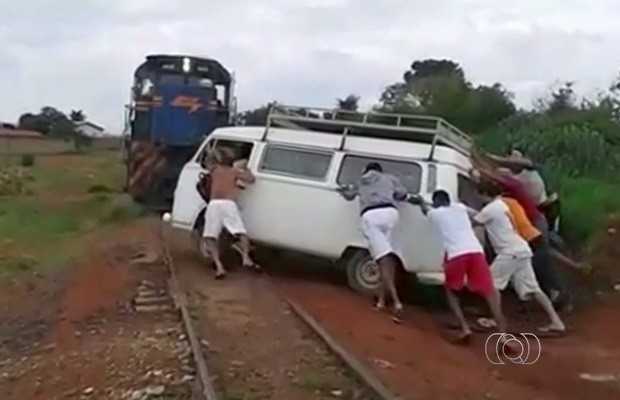 Moradores ajudam motorista a retirar carro do trilho do trem (Foto: Reprodução/TV Anhanguera)