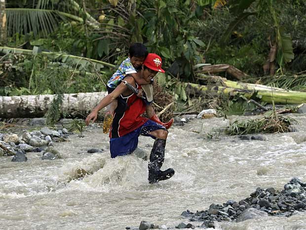 Morador atravessa rio na aldeia de Andap com uma criança nas costas. (Foto: Bullit Marquez / AP Photo )