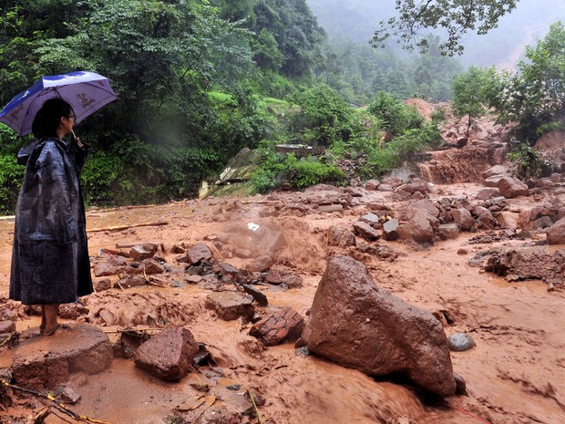 Mulher olha para um deslizamento de terra provocado pela chuva pesada no município de Zhongxing em Dujiangyan, sudoeste da China. (Foto: AFP)