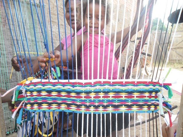 Raíssa e a mãe, Rosilene, dão forma a retalhos de tecido com a confecção de tapetes (Foto: Edivaldo Souza/G1)