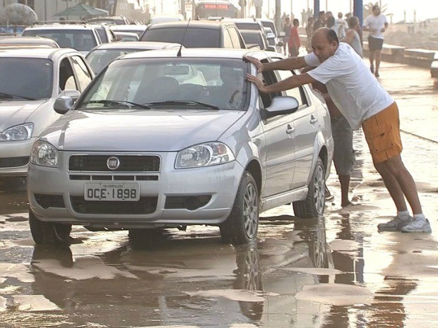 Veículo precisou ser empurrada para sair da avenida coberta de areia levada pela maré (Foto: TV Verdes Mares/Reprodução)