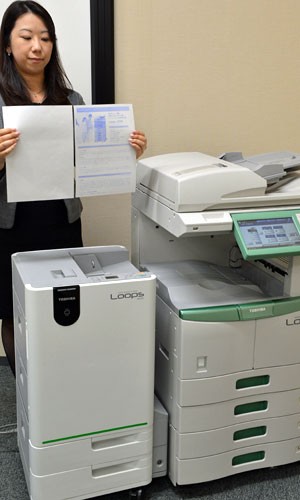 Funcionária da Toshiba demonstra nova impressora que reutiliza papéis (Foto: Yoshikazu Tsuno/AFP)