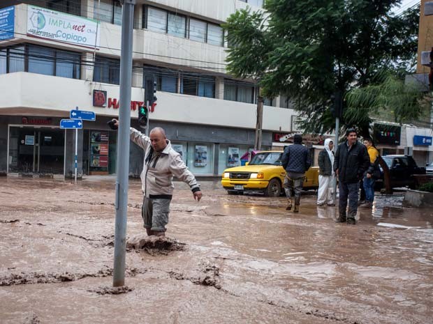Homem atravessa rua inundada por um rio de Copiapo, depois de forte temporal que afetou a região norte do Chile (Foto: AFP PHOTO/ALEX FUENTES)