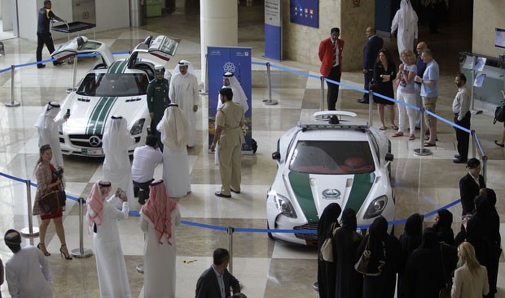 Visitantes fotografam Aston Martin One-77, à direita, e Mercedes SLS, que são usados pela polícia de Dubai (Foto: Kamran Jebreili/AP)