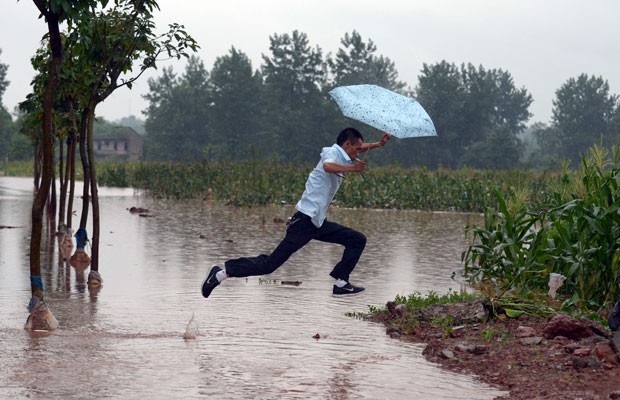 Imagem tirada no dia 22 mostra homem pulando poça em Chongqing, na China (Foto: AFP)