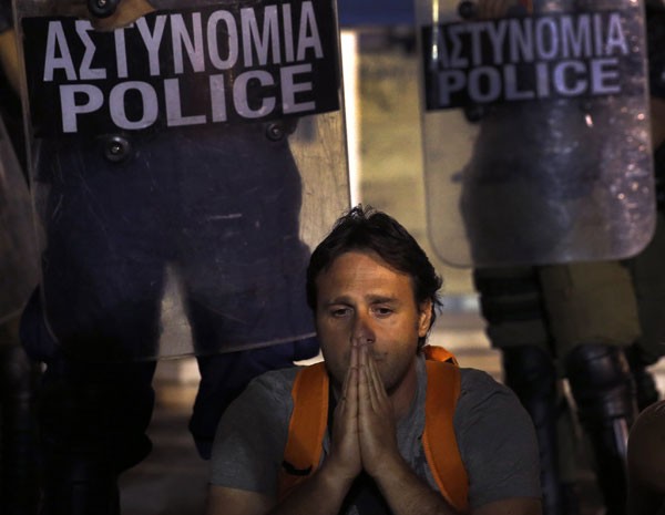 Servidor em frente aos policiais na sede do palamento grego em noite de votação. (Foto: Yannis Behrakis/Reuters)