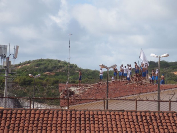 Presos voltaram a ocupar os telhados dos pavilhões co paus, pedras e bandeiras com siglas de facções criminosas (Foto: Andrea Tavares/ G1)