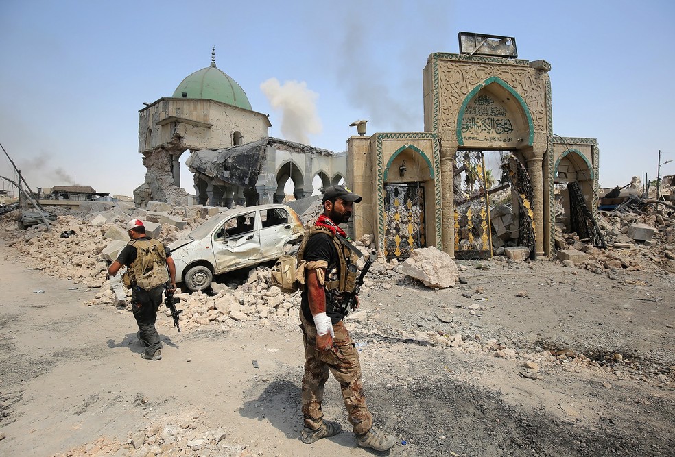 Membros de forças iraquianas passam em frente a mesquita destruída pelo Estado Islâmico em Mossul, no Iraque (Foto: AHMAD AL-RUBAYE / AFP)