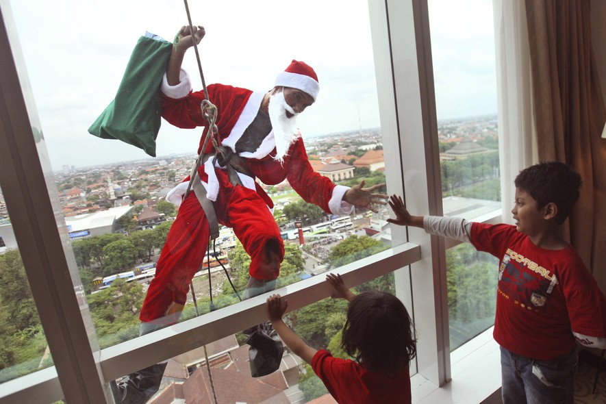 Em comemoração à chegada do Natal, funcionário de um hotel de Surabaya, na Indonésia, limpa as janelas do prédio vestido de Papai Noel - e faz a alegria da criançada