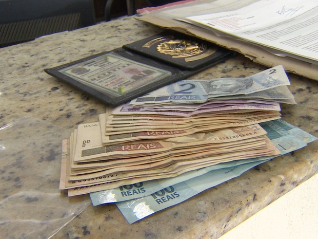 Dinheiro e carteira de detetive apreendidos com o idoso em Tremembé. (Foto: Reprodução/TV Vanguarda)