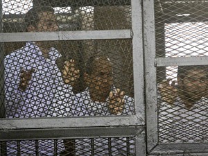 Os jornalistas da Al-Jazeera Baher Mohamed (à esquerda) e Peter Greste (ao centro) são vistos dentro de cela em julgamento no Cairo nesta quinta-feira (5) (Foto: Mohammed Abu Zaid/AP)