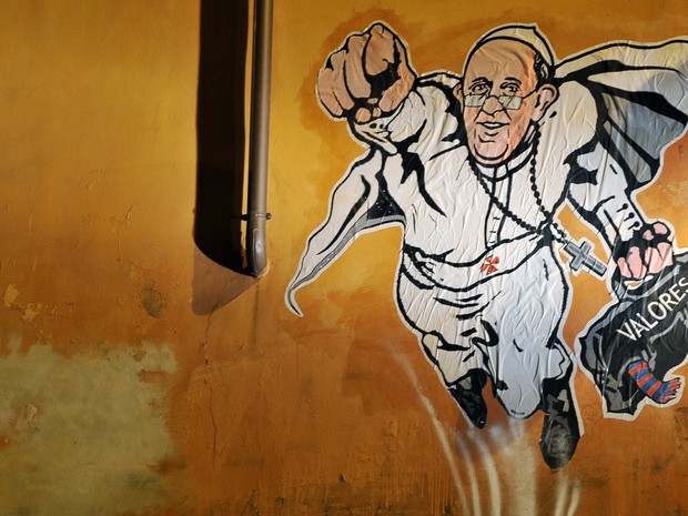 Arte de rua mostra Papa Francisco como super-herói voador, levando uma maleta de 'valores', em uma parede do centro de Roma, perto do Vaticano. Uma foto da obra do artista italiano Maupal foi postada no Twitter do canal de comunicação do Vaticano. (Foto: Tiziana Fabi/AFP)