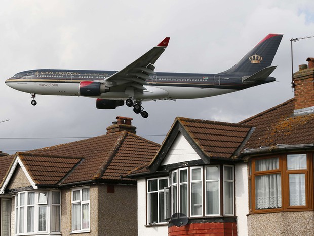 Avião passa por cima de casas antes de pousar no aeroporto de Heathrow, no oeste de Londres. O governo do primeiro-ministro David Cameron, descartou a possibilidade de construção de uma terceira pista no aeroporto de Heathrow antes da próxima eleição.  (Foto: Stefan Wermuth/Reuters)