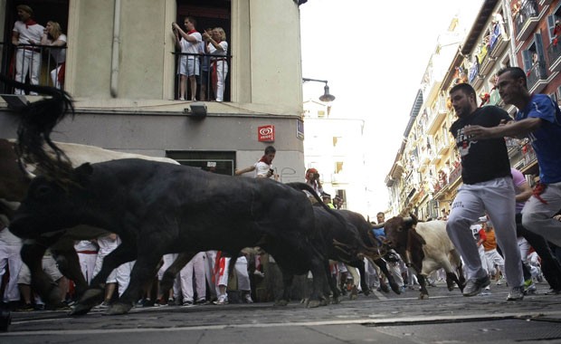 Corredores tentam fugir de touros durante a segunda corrida do festival de São Firmino em Pamplona (Foto: Joseba Etxaburu/Reuters)