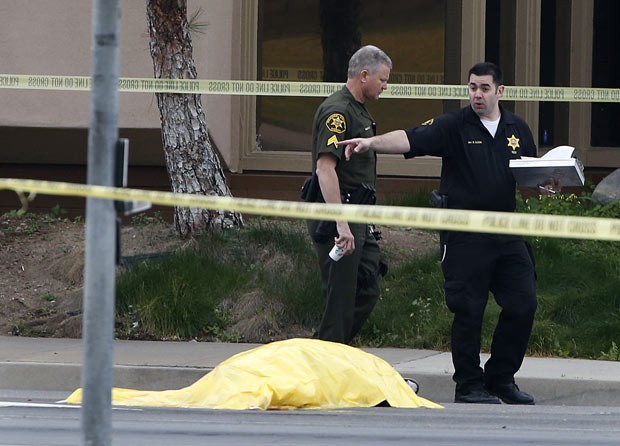 Policiais ao lado do corpo da primeira vítima do atirador, nesta terça-feira (19) no sul da Califórnia (Foto: AP)
