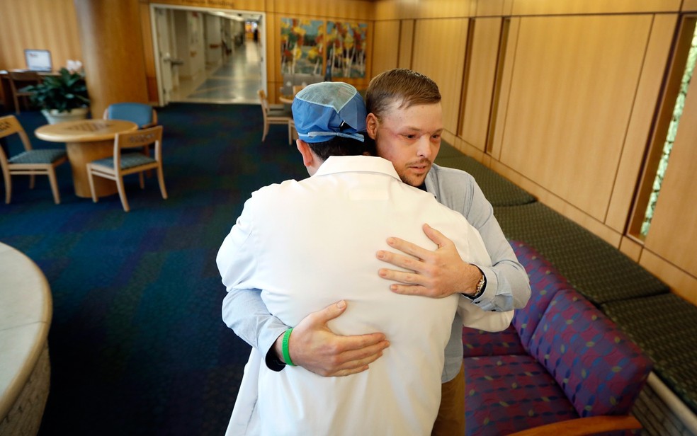  Andy Sandness abraça o cirurgião Samir Mardini, responsável pela cirurgia de transplante de rosto   (Foto: AP Photo/Charlie Neibergall)