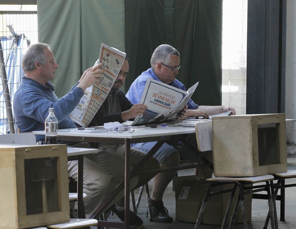 Mesários leem jornal enquanto esperam por eleitores no 2º turno das eleições do Chile, considerado com baixa adesão. (Foto: Eliseo Fernandez/Reuters)