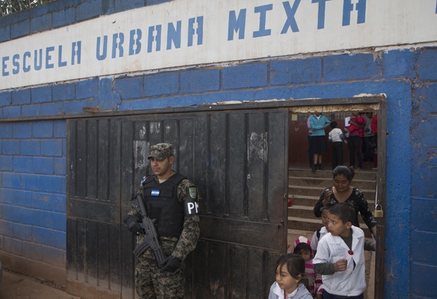 Policial militar faz guarda em frente a escola no última dia de aulas na capital Tegucigalpa (Foto: Esteban Felix/AP) Policial militar faz guarda em frente a escola no última dia de aulas na capital Tegucigalpa (Foto: Esteban Felix/AP)