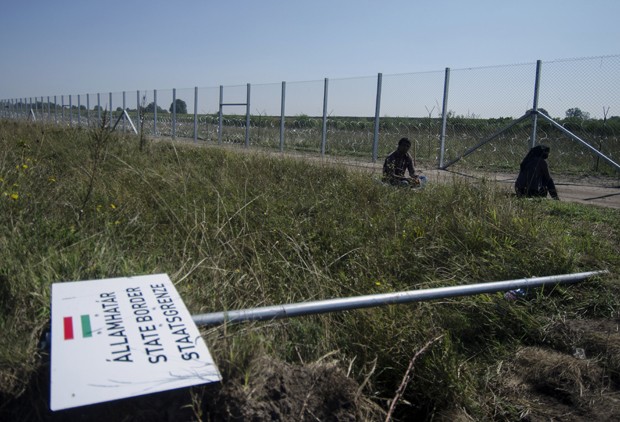 Migrante ficam atrás de cerca na fronteira da Hungria com a Sérvia (Foto: Csaba Segesvari / AFP)