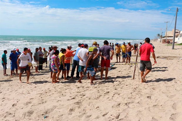 População se aglomerou para ver o corpo do pescador eda arraia, que foram encontrados sobre uma jangada (Foto: Marcelino Neto/G1)