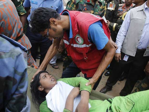 Equipes de resgate confortam uma sobrevivente, que estava presa nos escombros do edifício que desabou em Bangladesh. (Foto: Andrew Biraj / Reuters)