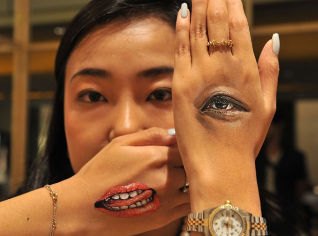 Modelo exibiu imagens superrealistas de um olho e boca nas mãos em um evento de arte em Tóquio (Foto: Yoshikazu Tsuno/AFP)