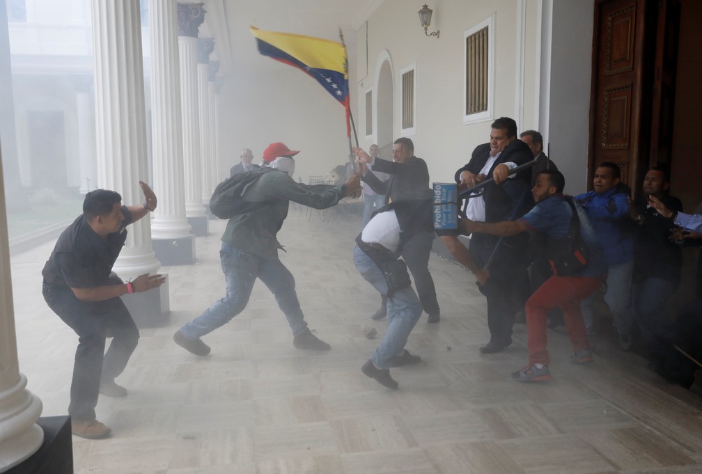 Manifestante pró Maduro com bandeira da Venezuela enfrenta pessoas na sede Assembleia Nacional, controlada pela oposição, em Caracas (Foto: REUTERS/Andres Martinez Casares)