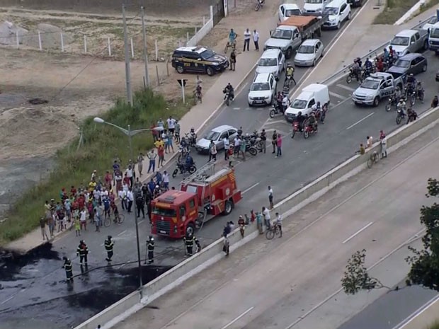 Bombeiros apagam fogo ateado em pneus e entulhos para bloquear rodovia (Foto: Reprodução / TV Globo)