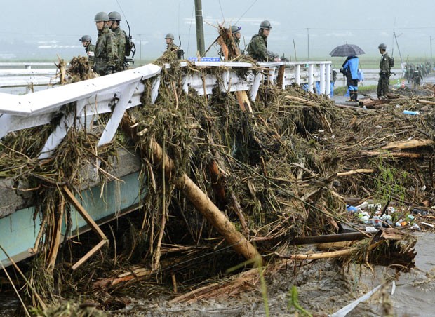 Militares observam árvores arrastadas pela chuva em Aso, na província japonesa de Kumamoto, neste sábado (14) (Foto: AP)