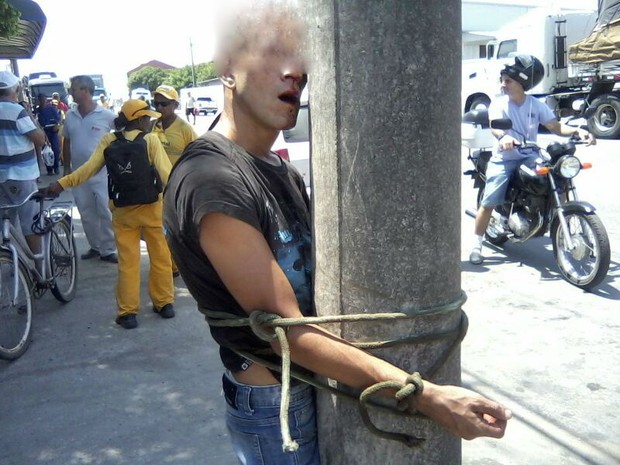 Preso no poste, assaltante recebeu socos e pontapés até sangrar (Foto: Polícia Militar/Divulgação)