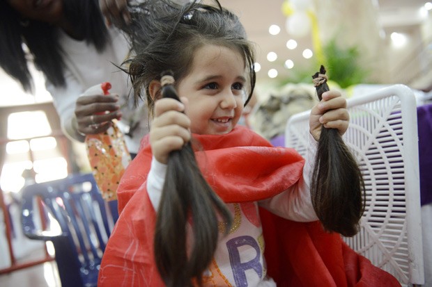 Menina segura mechas de cabelo doadas para campanha em Caracas. (Foto: AFP Photo/Leo Ramirez)