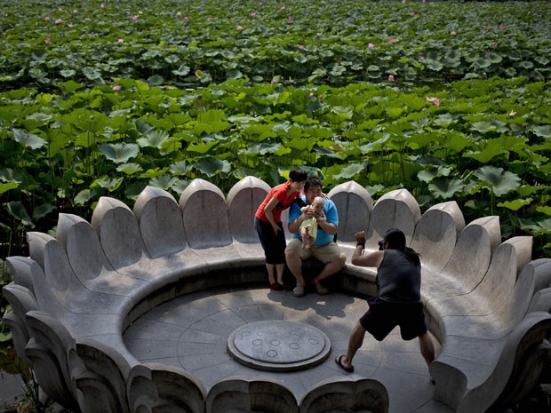 Família tira foto em ilha artificial em forma de flor de lótus no meio do lago (Foto: AP Photo/Andy Wong)
