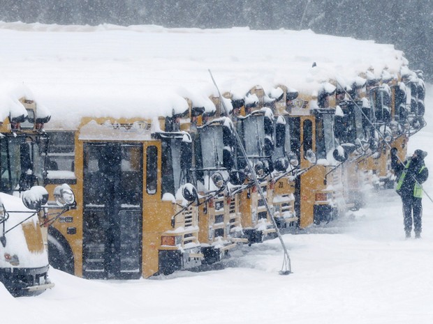 Motorista retira neve de ônibus escolares em Derry, New Hampshire, na segunda-feira (2) (Foto: AP Photo/Charles Krupa)