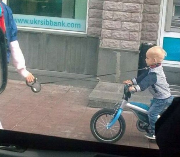 Criança usa coleira enquanto anda de bicicleta. (Foto: Reprodução)