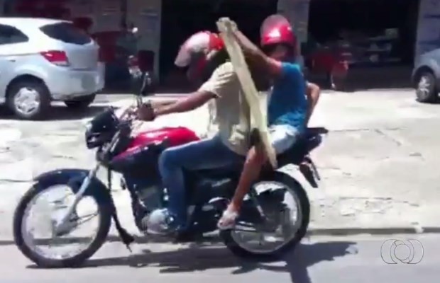 Porta é transportada entre piloto e garoto em Aparecida de Goiânia, Goiás (Foto: Reprodução/ TV Anhanguera)