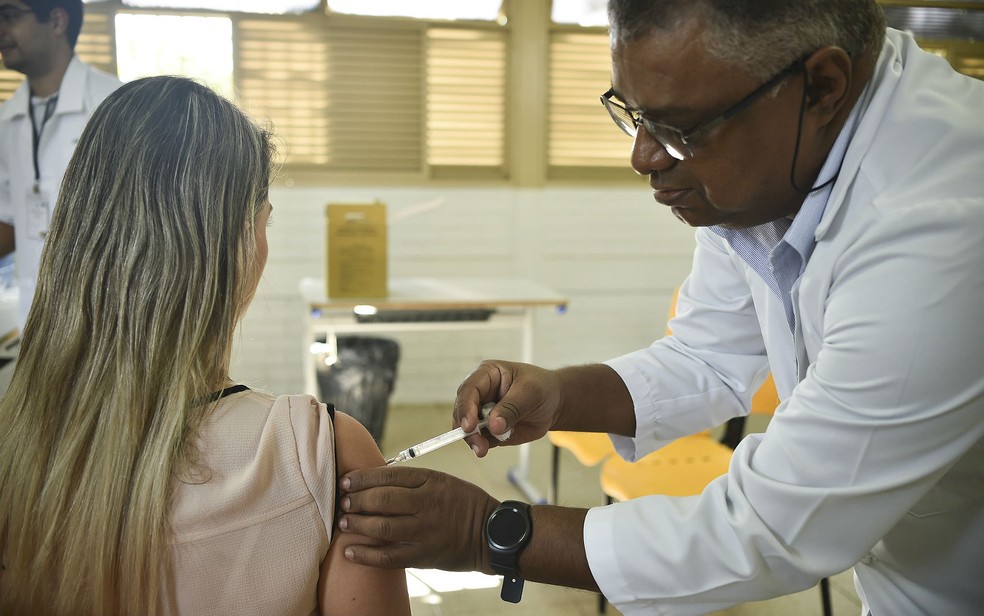 Enfermeiro vacina mulher contra gripe em posto de saúde no Distrito Federal (Foto: André Borges/Divulgação)