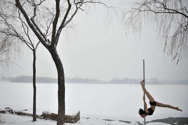 Chinesa faz performance de pole dance em meio à neve nesta quarta-feira (18) (Foto: China Daily/Reuters)