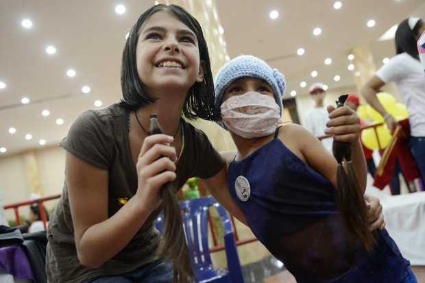 Menina que doou cabelo posa ao lado de paciente do hospital para crianças com câncer. (Foto: AFP Photo/Leo Ramirez)