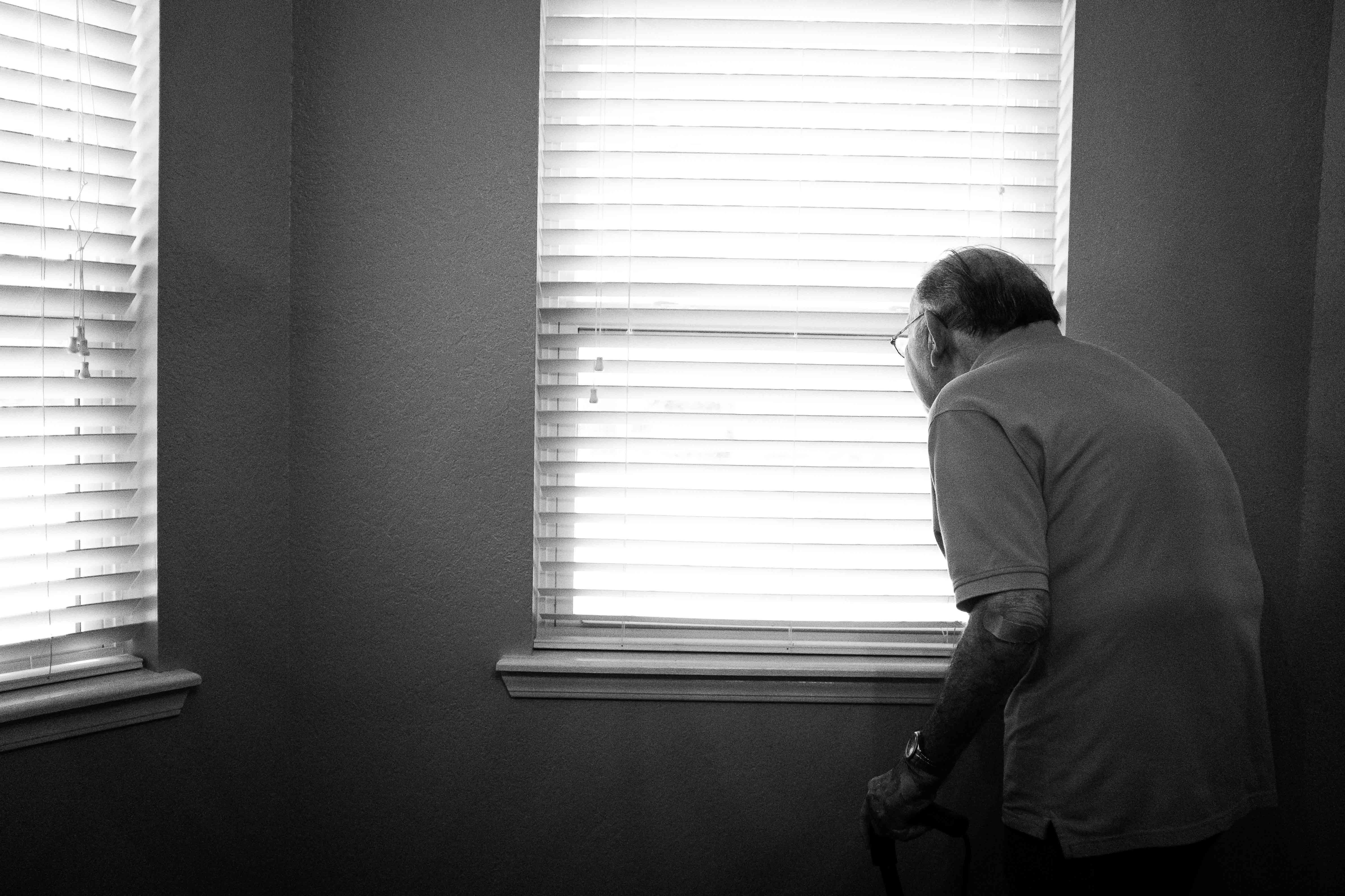 Idosos são os que mais sofrem com depressão e acreditam em mitos, mostra pesquisa. Acima: idoso espiando pelas frestas da cortina dentro de casa. (Foto: Alex Boyd/Unsplash)