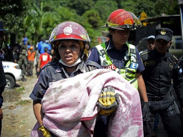 Criança é carregada no resgate de vítimas de um deslizamento de terra na Guatemala nesta sexta-feira (2) (Foto: AFP PHOTO / Johan ORDONEZ)