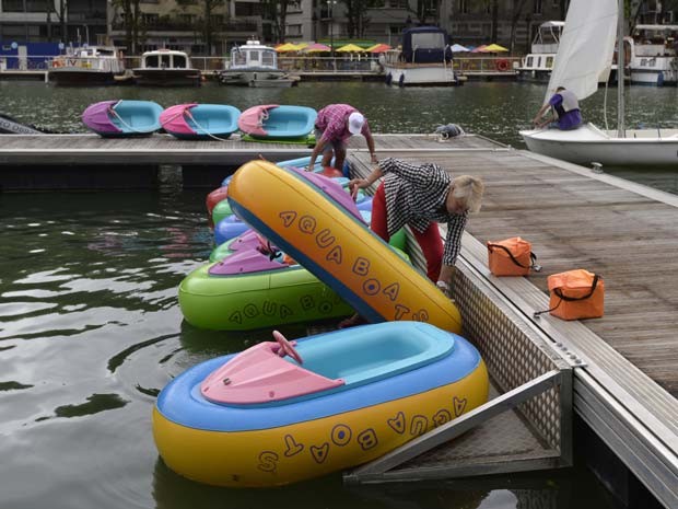 Pessoas preparam barcos no rio Sena, em Paris, durante a inauguração da 14ª edição da 'Paris plages' (Foto: AFP PHOTO / MIGUEL MEDINA)