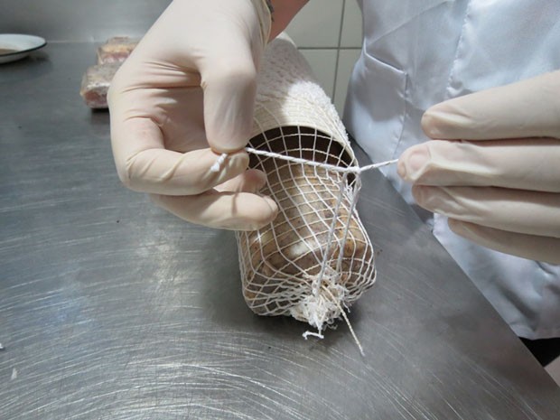 Lombo é colocado em uma rede elástica, que ajuda a dar o formato do produto final.  (Foto: Valdinei Guimarães/G1 ES)