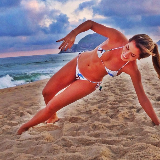 Foto Uma mulher em um biquíni fazendo uma pose de yoga na praia