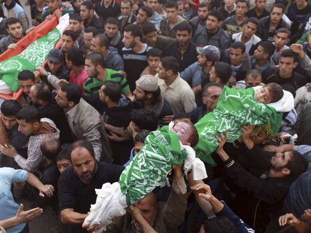 Palestinos carregam os corpos de duas crianças e do pai delasdurante cortejo em Beit Lahiya, no norte da Faixa de Gaza. Os três foram mortos por um ataque aéreo israelense que atingiu a casa da família na segunda-feira (19), segundo autoridade do Hamas. (Foto: Mohammed Salem/Reuters)