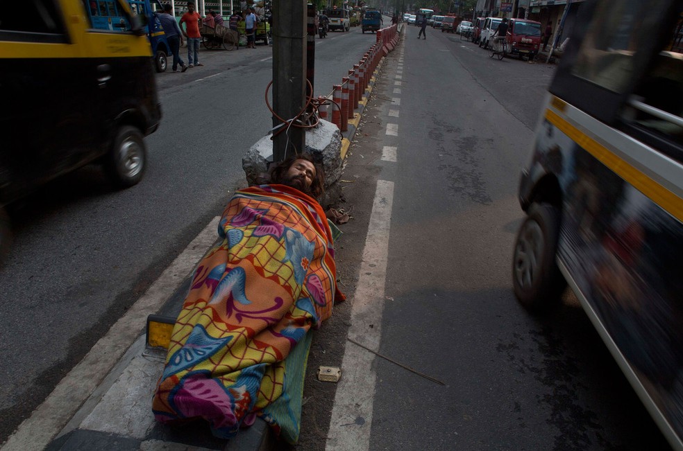 Morador de rua dorme em área movimentada em Gauhati, na Índia. Segundo pesquisas, pobreza pode ter impacto no cérebro  (Foto: AP Photo/Anupam Nath)